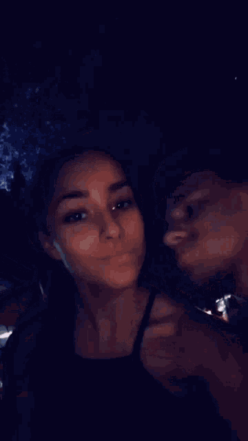 a man and a woman are kissing in front of a mirror .