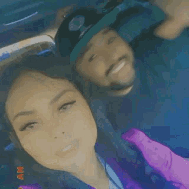 a man and woman are kissing in a car . the woman is wearing a purple jacket .