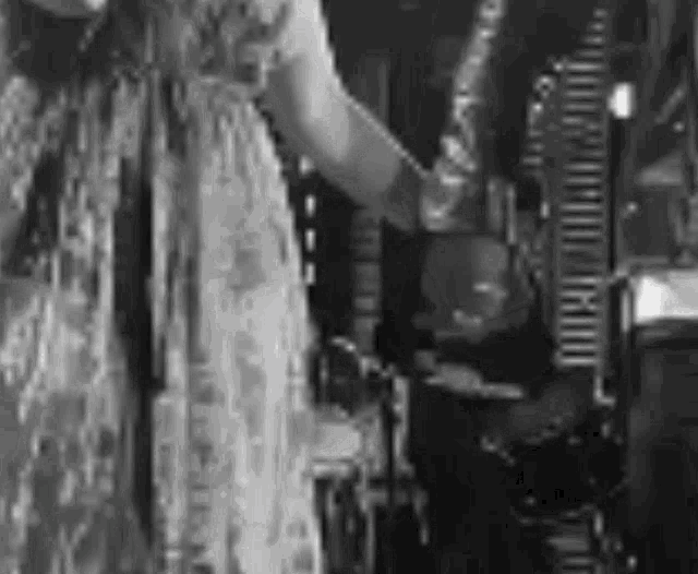 a woman in a long dress is singing into a microphone while standing in front of a piano .