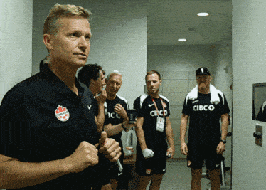 a group of men are standing in a hallway wearing shirts that say cibco