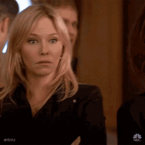 a woman is making a funny face while sitting in a crowd .