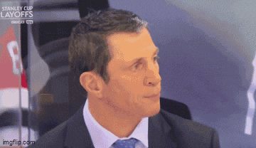 a man in a suit and tie is sitting in front of a stanley cup layoffs banner