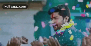 a man is standing in front of a crowd of people surrounded by confetti and flowers .