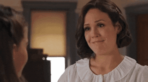 a woman in a white shirt is smiling and looking at another woman .