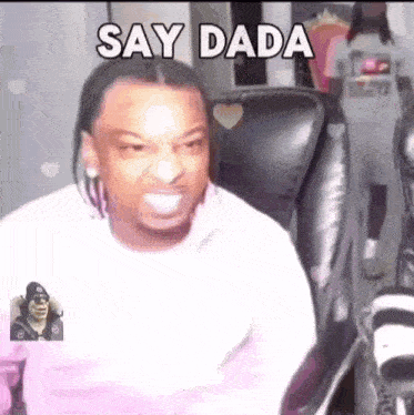 a man is sitting in a chair and smiling with the words `` say dada '' written on his face .