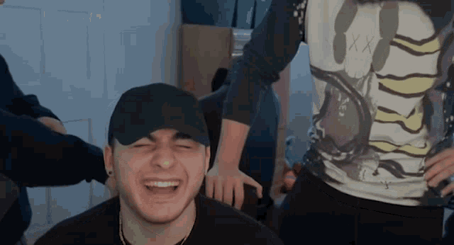 a man wearing a black hat is laughing in front of another man wearing a shirt that says " xx " on it