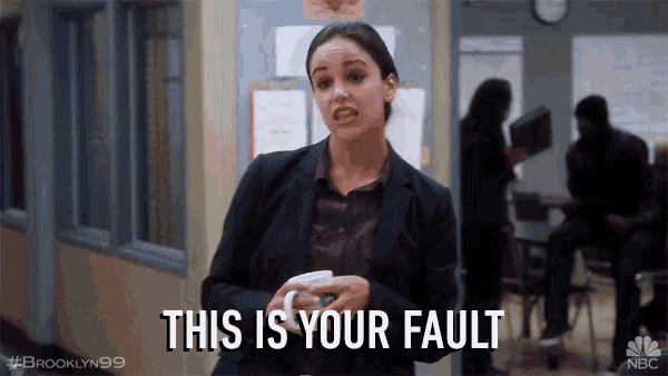 a woman in a suit is holding a cup and says " this is your fault "