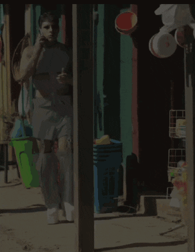 a man talking on a cell phone in front of a store with buckets