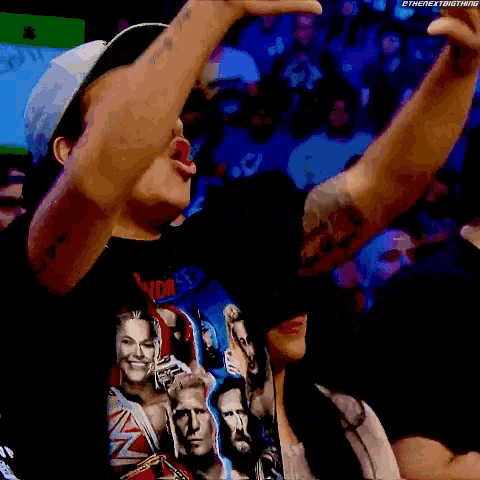 a man wearing a t-shirt with wrestlers on it is cheering