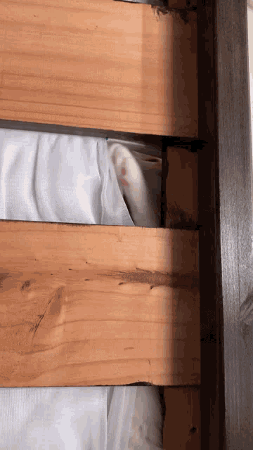 a close up of a wooden bed frame with a white blanket