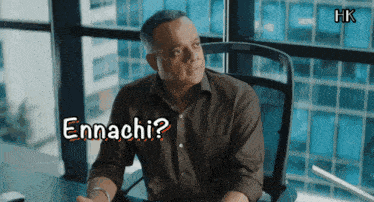 a man is sitting at a desk with the words ennachi written on the screen