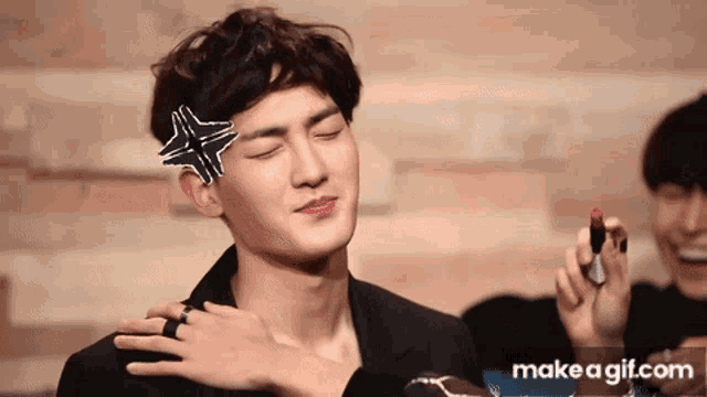 a man with a star on his head is holding a lipstick in his hand