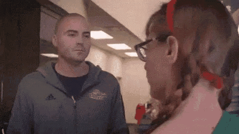 a man and woman are standing next to each other in a hallway .