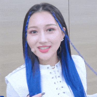 a woman with blue hair is wearing a white top