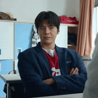 a man with his arms crossed is wearing a blue jacket and a red shirt with the letter z on it