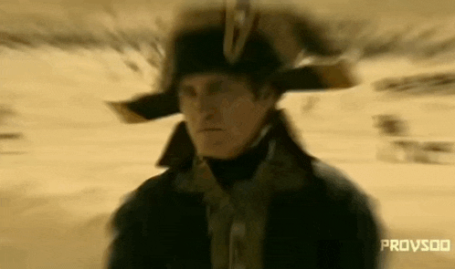a man in a military uniform is walking in the desert wearing a hat .