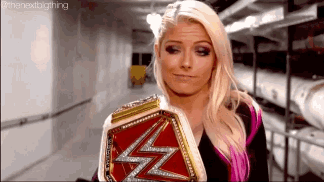 a woman is holding a wrestling championship belt in a dimly lit hallway .