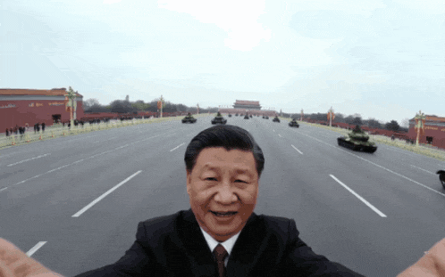 a man in a suit and tie is taking a selfie in front of a military parade