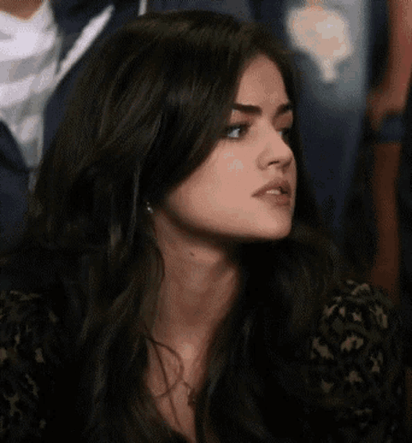 a woman with long dark hair is sitting in a crowd of people .