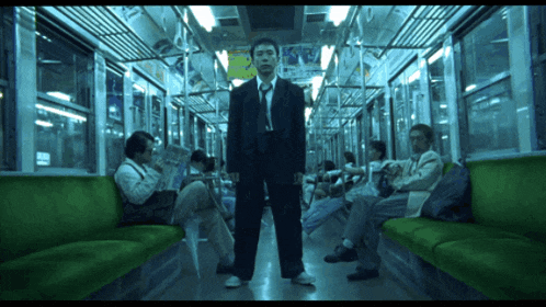 a man in a suit and tie stands in the middle of a train
