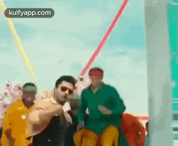 a group of men are dancing on a boat and one of them is wearing a green shirt .
