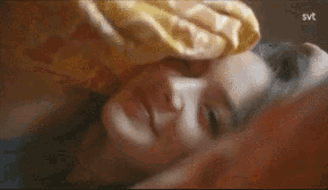 a close up of a woman laying in bed with a blanket over her face .