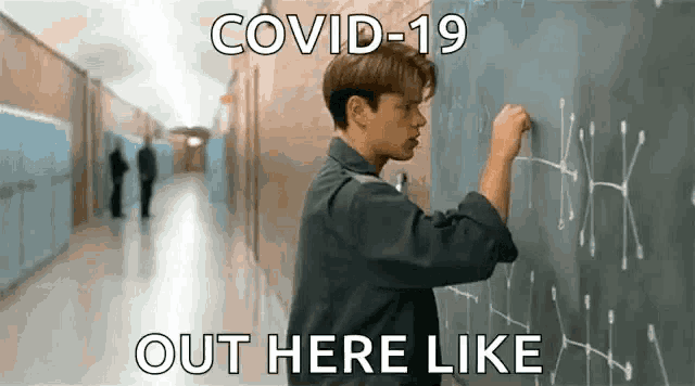 a man is writing on a blackboard in a hallway with a caption that says `` covid-19 out here like '' .