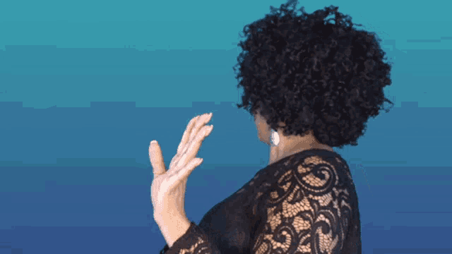 a woman with curly hair wearing a black lace shirt