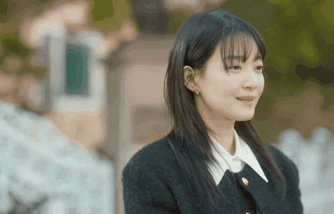 a woman in a black sweater and white shirt smiles