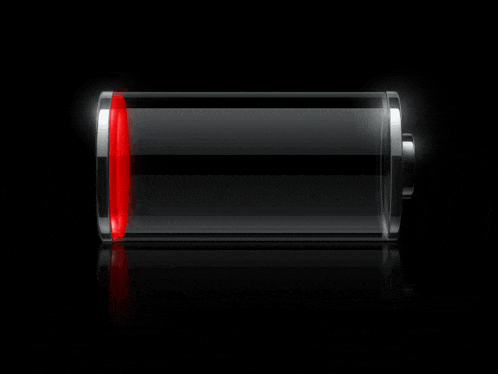 a green battery is glowing in the dark on a black surface