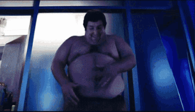 a shirtless man with a large belly is standing in front of a blue door