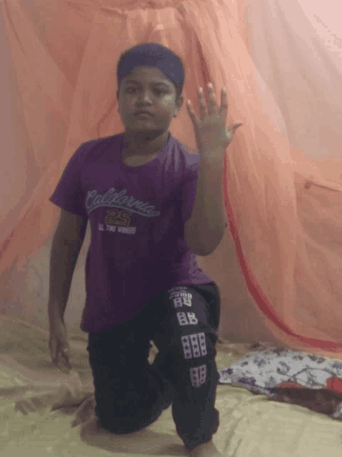 a boy wearing a purple california shirt kneeling down