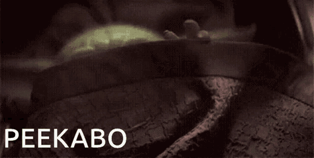 a baby yoda is laying in a blanket with the word peekaboo written above it