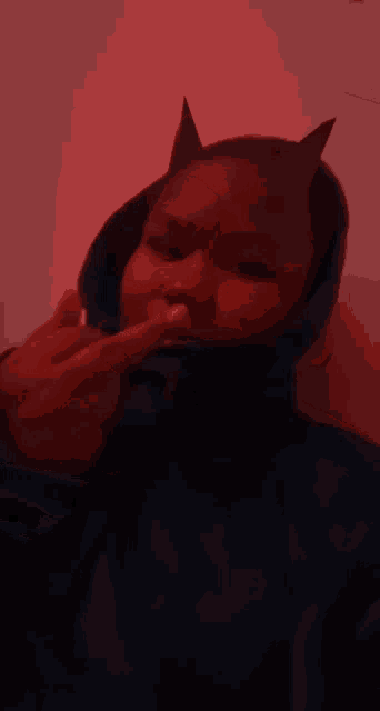 a person wearing devil horns and a blue jacket giving the middle finger