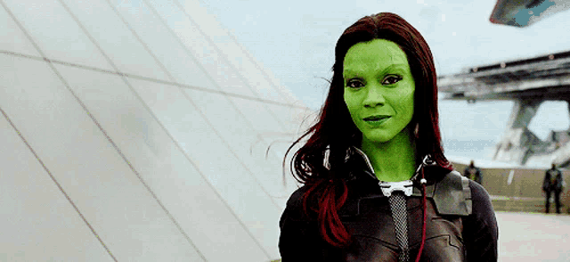 a woman with green hair and red highlights is wearing a black jacket