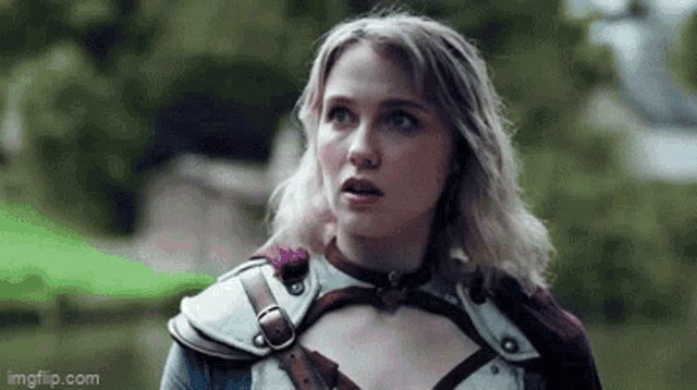 a woman in a costume is standing in a field with a green light coming out of her mouth .