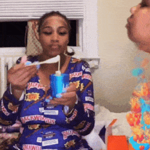 a woman wearing a blue shirt that says backwoods on it is eating something