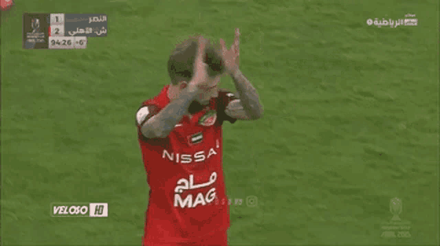 a soccer player wearing a red jersey that says nissan on it
