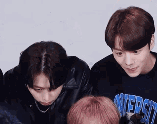 a group of young men are standing next to each other and one of them is wearing a shirt that says university on it