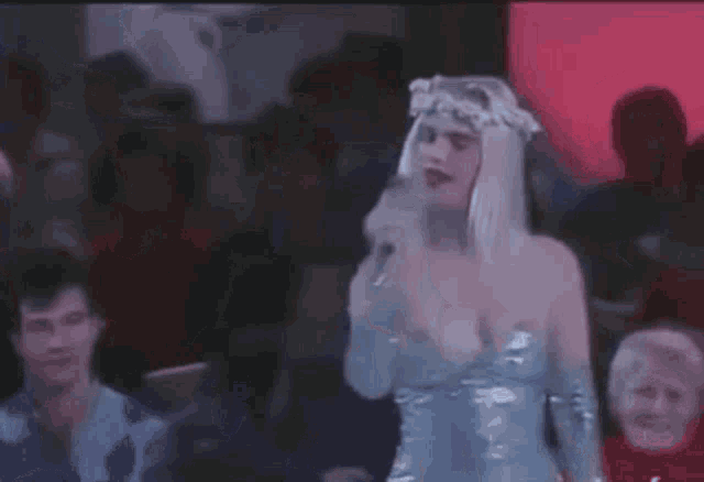 a woman in a silver dress is dancing in a crowd of people in a club .