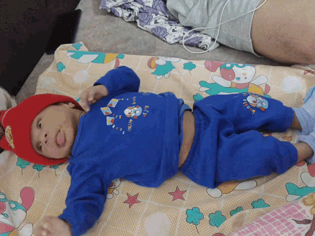a baby wearing a red hat and a blue shirt with a clock on it