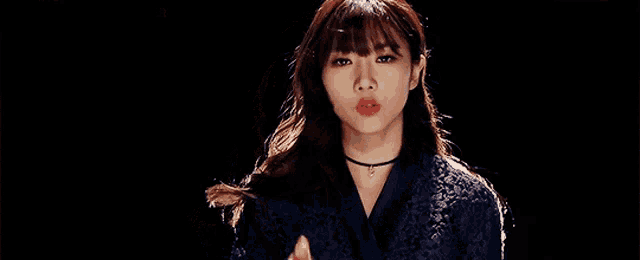 a woman in a blue jacket is pointing at the camera with her finger .