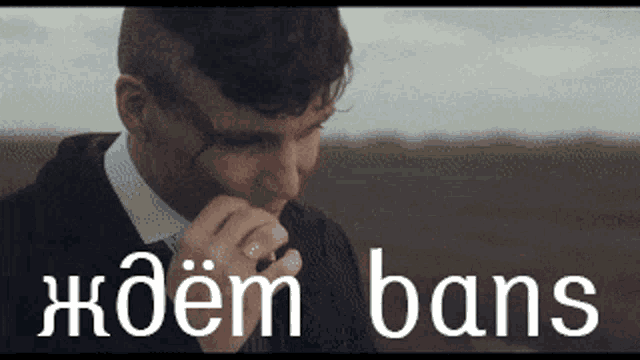 a man in a suit and tie is smoking a cigarette in a field with the word bans below him
