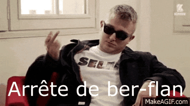 a man wearing sunglasses and a t-shirt that says self is giving the middle finger