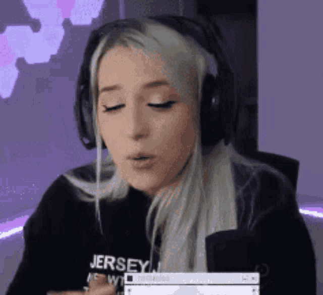 a woman wearing headphones and a jersey on her shirt is blowing a kiss .