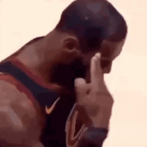 a basketball player is covering his face with his hand and making a middle finger gesture .