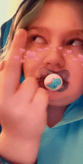 a girl with a pacifier in her mouth shows the middle finger
