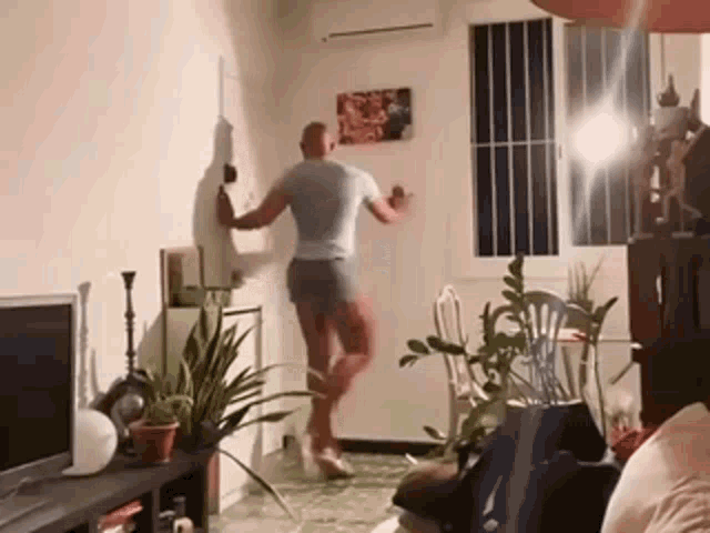 a man is dancing in a living room in front of a tv .