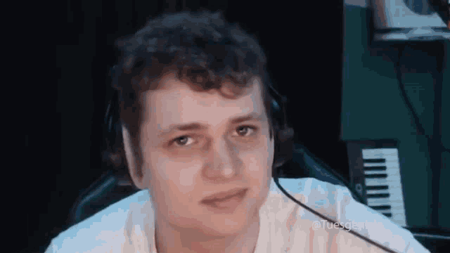 a man with curly hair is wearing headphones and looking at the camera .