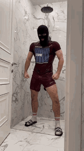a man standing in a shower wearing a shirt that says " core "